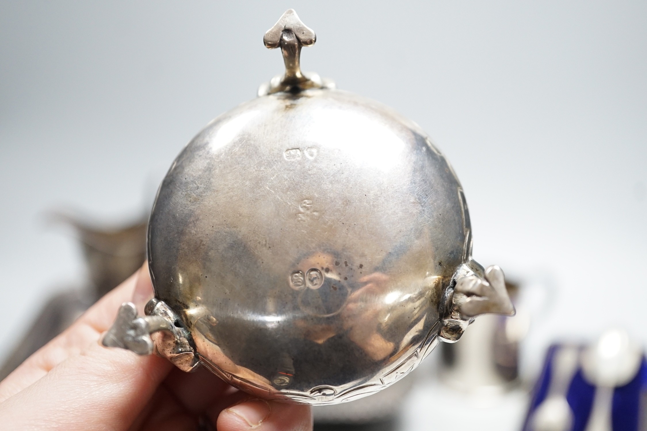 A small collection of English silver to include a pair of Victorian cauldron salts, two small beakers, a cream jug with presentation script, a George IV silver mustard pot with hinged cover, London, 1823 and a boxed chri